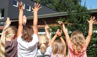 Kinder strecken die Hände in den Himmel