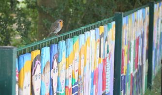 Ein Rotkehlchen sitz als Zaungast auf dem Kindergartenzaun